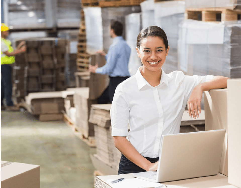 woman smiling at computer in warehouse. on-demand staffing