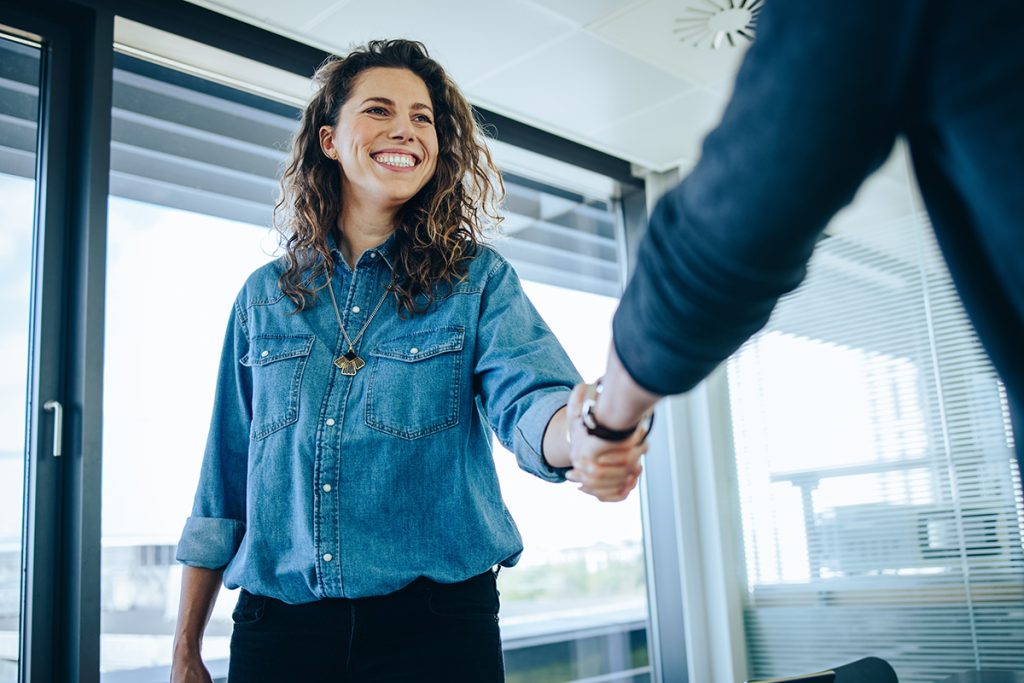 Recruitment manager shakes her hand with male candidate as he interviews for the job.