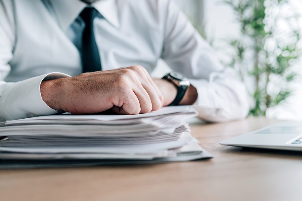 Businessman with stack of resumes and documentation, selective focus